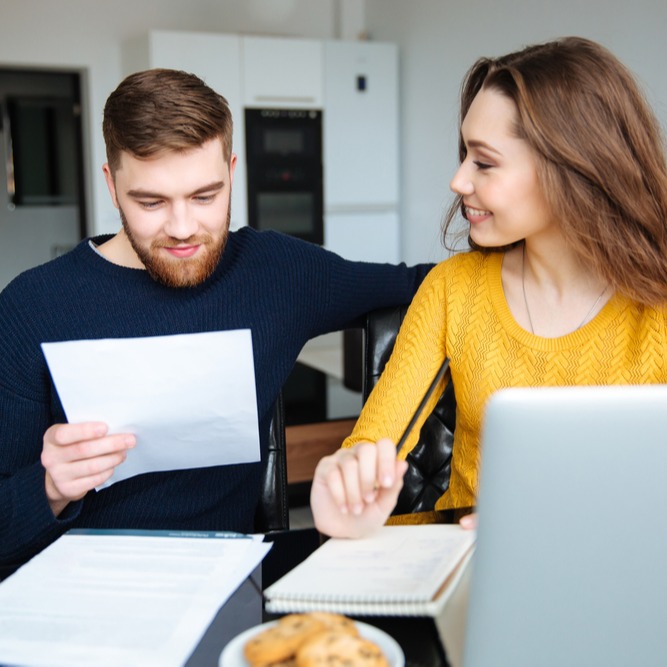 Happy young couple calculating bills at home-1